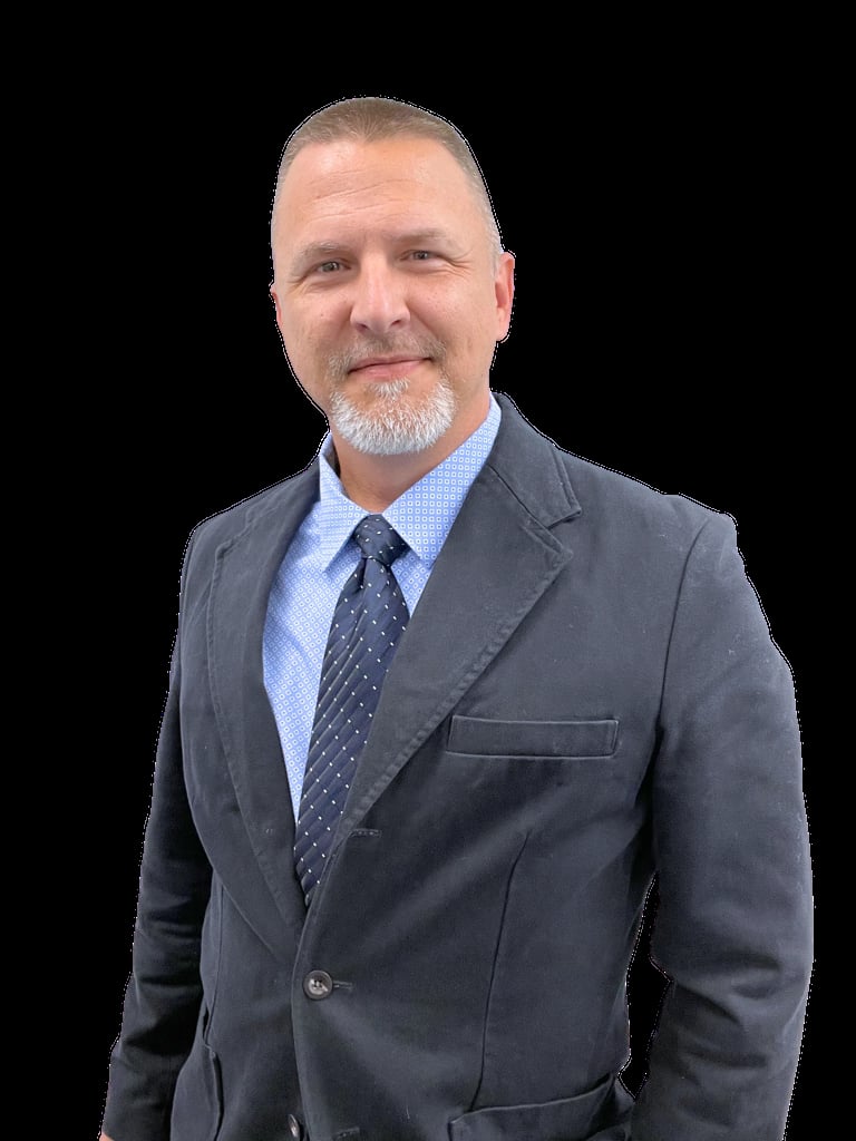 Professional headshot of a middle-aged man with goatee wearing gray blazer, light blue shirt, and dark tie against black background